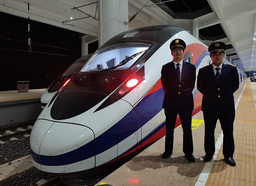 劉銀能（右一）與中國(guó)師父鄔俊鴻在動(dòng)車組前合影。受訪者供圖